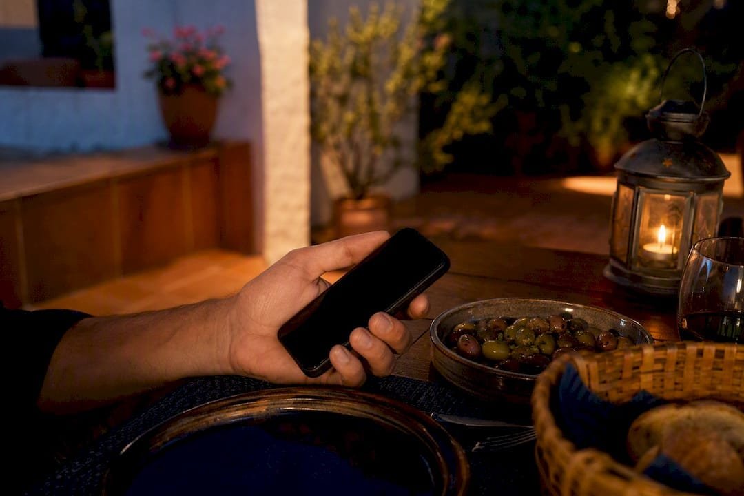 Hand holding smartphone at restaurant table